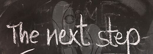 „The next step“ mit Fußspuren auf Tafel