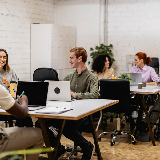 Diverse Gruppe sitzt an Schreibtischen und arbeitet