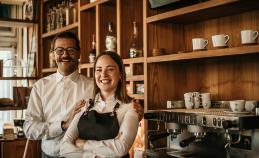 Zwei Café-Mitarbeitende lächeln stolz hinter der Theke.